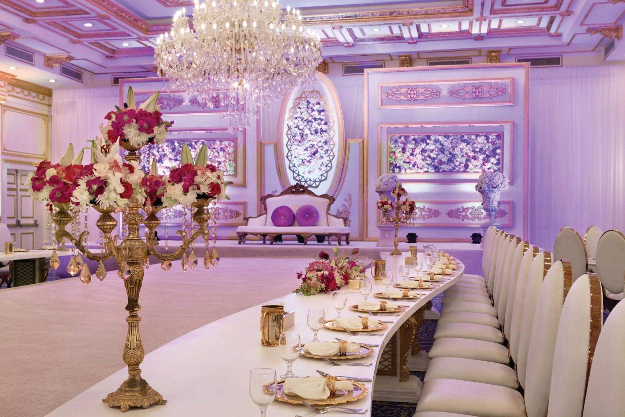 Grand Regency Doha, Trademark Collection By Wyndham Екстер'єр фото The photo displays an elegantly decorated banquet or dining hall. It features a long, curved table set for a formal event, with fine china and floral centerpieces. Luxurious decorations include a grand chandelier hanging from the ceiling, and the wal