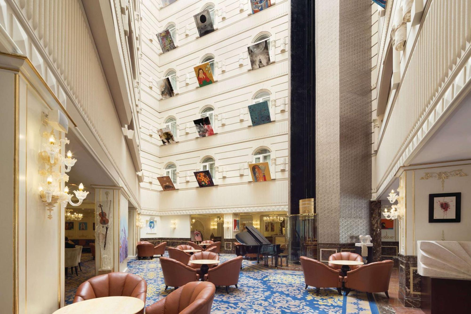 Grand Regency Doha, Trademark Collection By Wyndham Екстер'єр фото The photo depicts the interior of a spacious, upscale hotel lobby. The design features high ceilings and multiple levels, with large windows that create a bright and airy atmosphere. Elegant light fixtures adorn the walls, and the floor is covered wi