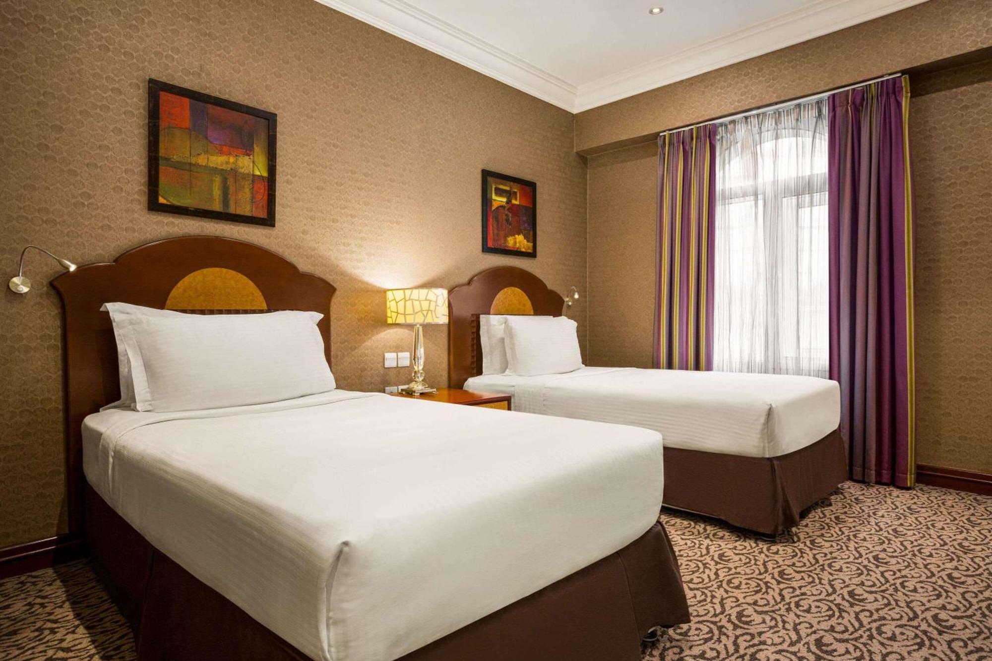 Grand Regency Doha, Trademark Collection By Wyndham Екстер'єр фото The photo shows a hotel room featuring two single beds with white bedding and dark brown upholstered headboards. There is a bedside table with a lamp between the beds. On the walls are two abstract paintings, and large windows dressed with sheer curt